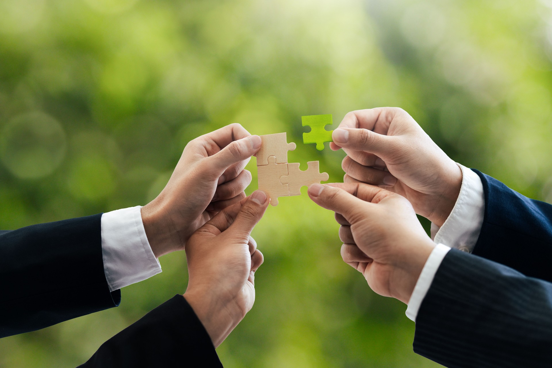 Office workers holding a jigsaw puzzle, teamwork and unity. Charity, volunteering, problem solving, business unity, business teamwork, success and strategy. Green background.